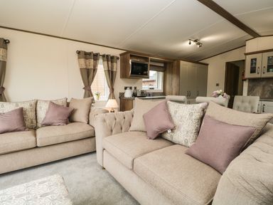 A living room with beige sofas and patterned cushions at Ashton Lodge - Sherwood 4 South Lakeland Leisure Village