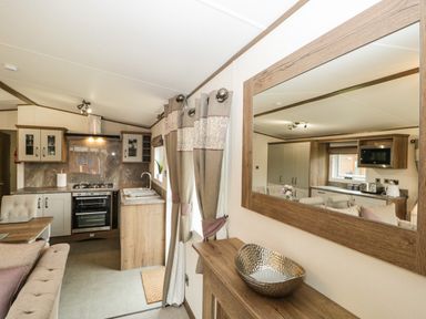 A kitchen and living area with sink oven cabinets curtains and mirror at Ashton Lodge - Sherwood 4 in South Lakeland Leisure Village