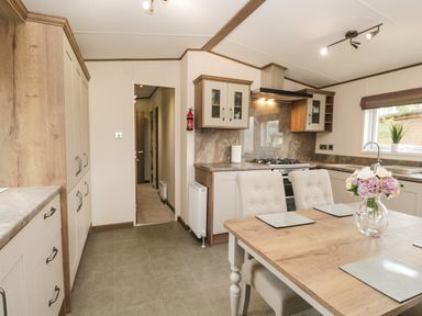 A kitchen with a dining table chairs cabinets a gas stove and a window at Ashton Lodge - Sherwood 4 in South Lakeland Leisure Village