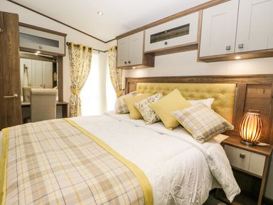 A bedroom with a bed with cushions and a bedside table with a lamp at Ashton Lodge - Sherwood 4 in South Lakeland Leisure Village