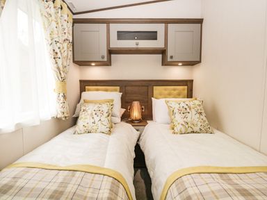 A bedroom with two single beds side by side with floral cushions and a lamp between at Ashton Lodge - Sherwood 4 in South Lakeland Leisure Village