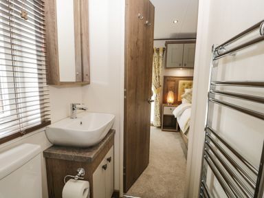 A bathroom sink and toilet with a door leading to a bedroom at Ashton Lodge - Sherwood 4 South Lakeland Leisure Village