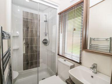 A bathroom with a glass shower enclosure toilet sink mirror and window blinds at Ashton Lodge - Sherwood 4 South Lakeland Leisure Village