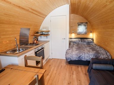A small wooden room with a kitchen area a bed and a dining table at Goose Pod Near Clifton Upon Teme