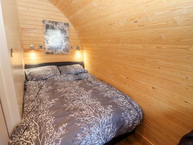 A bedroom with a double bed and wooden paneled walls at Goose Pod Near Clifton Upon Teme