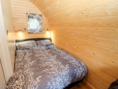 A bedroom with a double bed and wooden walls at Gander Pod Near Clifton Upon Teme