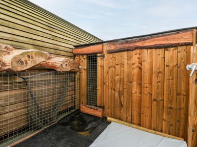 An outdoor enclosure with wooden panels and wire mesh at Gander Pod Near Clifton Upon Teme