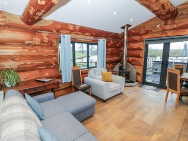 A living room with a sofa, fireplace, and table at Cedar Cabin at Salford Court Farm Fishing Cabins near Clifton Upon Teme