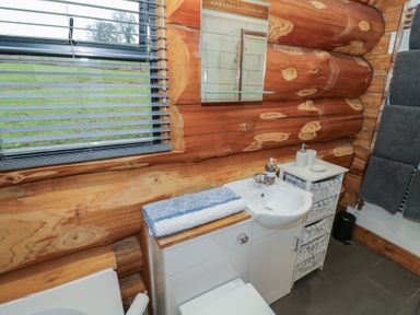 A bathroom with wooden wall and sink at Cedar Cabin at Salford Court Farm Fishing Cabins near Clifton Upon Teme