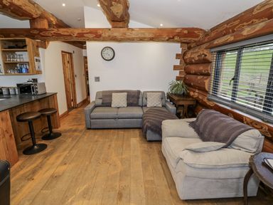 A living room with sofas and a kitchen counter at Douglas Cabin at Salford Court Farm Fishing Cabins near Clifton Upon Teme