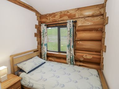 A bedroom with a bed and window at Douglas Cabin at Salford Court Farm Fishing Cabins near Clifton Upon Teme