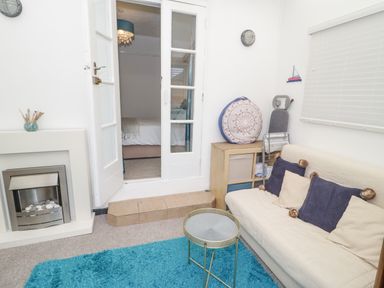 A living room with a small table a white sofa cushions a blue rug and a fireplace at Cove House in Kinmel Bay