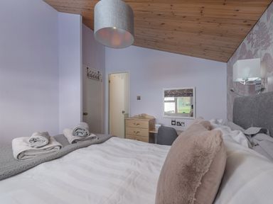 A bedroom with a bed pillows folded towels a desk chair chest of drawers and a window at Oaks One Swarland near Felton