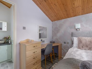 A bedroom with a bed a desk a chair and a chest of drawers at Oaks One in Swarland near Felton
