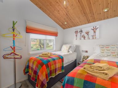 A bedroom with two single beds colorful blankets and animal wall art at Oaks One Swarland near Felton