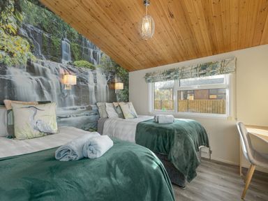A bedroom with two single beds and a waterfall mural on the wall at Oaks One Swarland near Felton