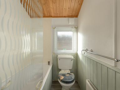 A bathroom with a toilet and bathtub next to a window at Oaks One Swarland near Felton