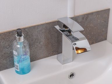 A bathroom sink with a modern chrome faucet and a blue liquid soap dispenser at Oaks One Swarland near Felton