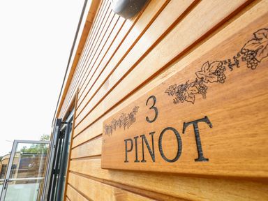 A wooden exterior wall with a sign that says 3 PINOT and a glass door at Pinot in Seaview