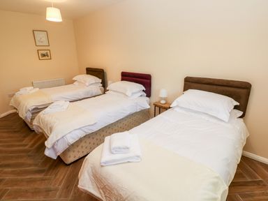 A bedroom with three single beds and folded towels at 1 The Warren in Robeston Wathen near Narberth