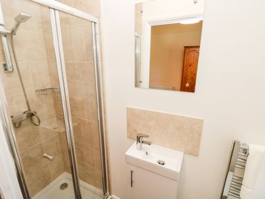 A bathroom with a glass shower enclosure a small sink with a faucet a mirror and a towel rail at 1 The Warren in Robeston Wathen near Narberth