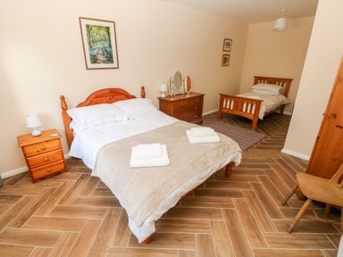 A bedroom with a double bed and a single bed wooden furniture and folded towels at 1 The Warren in Robeston Wathen near Narberth