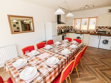 A kitchen with dining table set for eight and red chairs at 1 The Warren in Robeston Wathen near Narberth