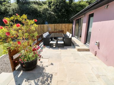 An outdoor patio with a dining table and chairs near a purple building at 1 The Warren in Robeston Wathen near Narberth