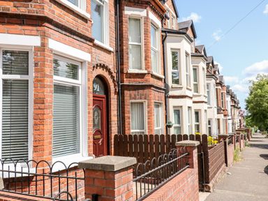 A row of terraced brick houses with fences along a sidewalk at Number 91 in Belfast County Antrim