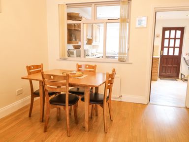 A dining area with a wooden table and four chairs next to a window opening to a kitchen at Number 91 in Belfast County Antrim