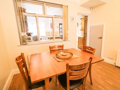 A dining area with a wooden table and four chairs near a window opening to a kitchen at Number 91 in Belfast County Antrim