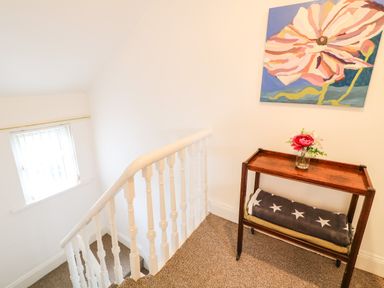 A staircase with white railings next to a wooden table holding a vase with flowers and blankets at Number 91 in Belfast County Antrim