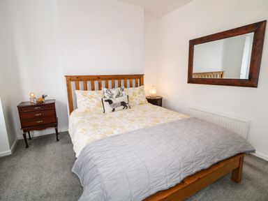 A bedroom with a wooden bed frame a large mirror on the wall and two bedside tables at Number 91 in Belfast County Antrim