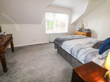 A bedroom with a bed pillows blanket bedside table lamp window chest of drawers and wooden table at Number 91 in Belfast County Antrim