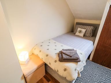 A small bedroom with a single bed covered in bee patterned bedding and a bedside table with a lamp at Number 91 in Belfast County Antrim