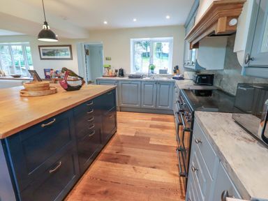 A kitchen with blue cabinets wooden island and appliances at Flaska House in Troutbeck Near Penrith