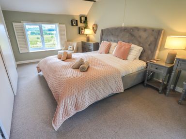 A bedroom with a large bed two bedside tables a chair a window and a lamp at Flaska House in Troutbeck Near Penrith