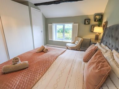 A bedroom with a bed pillows towels on the bed a chair a window and a lamp at Flaska House Troutbeck Near Penrith