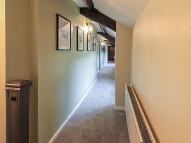A hallway with framed pictures on one wall and a radiator on the opposite wall at Flaska House in Troutbeck Near Penrith