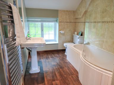 A bathroom with a pedestal sink towel rack toilet and bathtub at Flaska House in Troutbeck Near Penrith