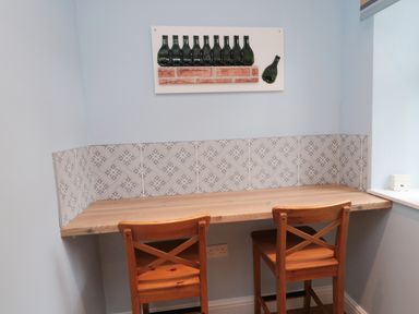 A small wooden table with two wooden chairs and a decorative wall art above at 1 Roddam Rigg Cottage Roddam near Wooler