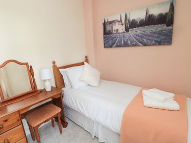A bedroom with a single bed a wooden dressing table with mirror and a painting on the wall at 1 Roddam Rigg Cottage Roddam near Wooler