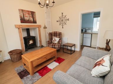 A living room with a wood burning stove armchair and sofa at 1 Roddam Rigg Cottage in Roddam near Wooler
