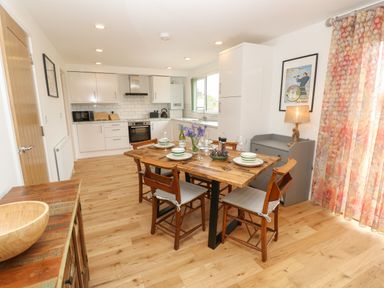 A kitchen and dining area with wooden table and chairs set for four people at Syrah in Seaview