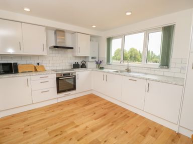 A kitchen with white cabinets wooden floor oven microwave and a window with green blinds at Syrah in Seaview