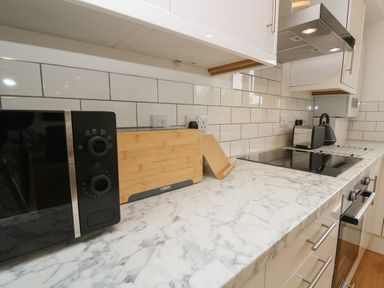 A kitchen countertop with a microwave cutting boards stove toaster and kettle at Syrah in Seaview