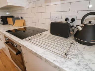 A kitchen countertop with a black toaster and kettle a metal drying rack and a built in oven at Syrah in Seaview