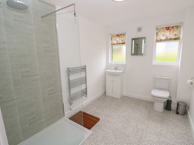 A bathroom with a walk-in shower sink toilet and patterned floor tiles at Syrah Seaview