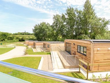 A row of modern wooden cabins with railings surrounded by grass and trees at Syrah in Seaview