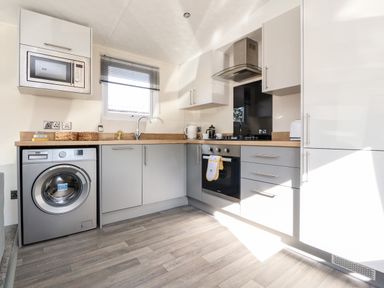 A kitchen with washing machine microwave oven stove and cabinets at Hawthorn Lodge in South Lakeland Leisure Village